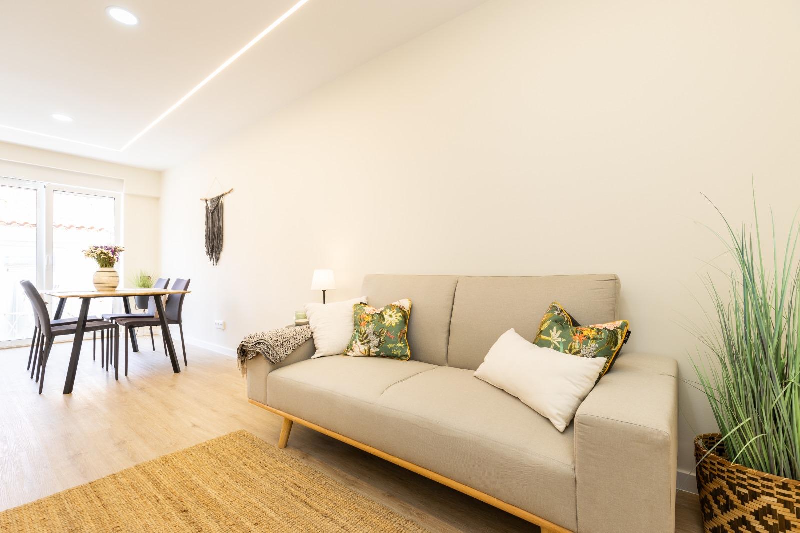 Renovated living room with sofa, dining table and daylight from the balcony