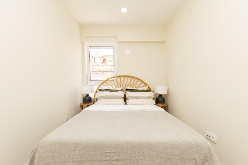 Bedroom seen head on, window looking over the rooftops