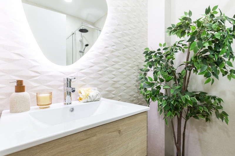 Bathroom with basin and backlit round mirror