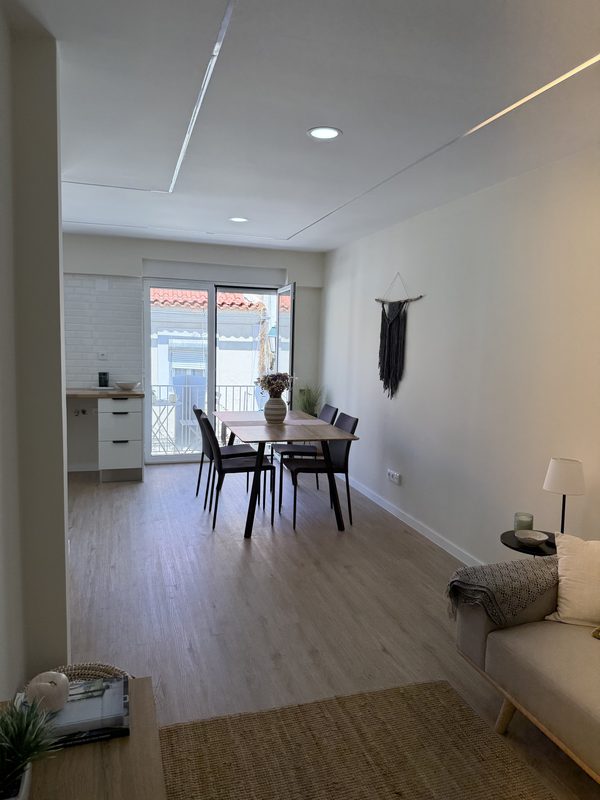 Sala em plano aberto: sofá, mesa de jantar e as portas da varanda ao fundo