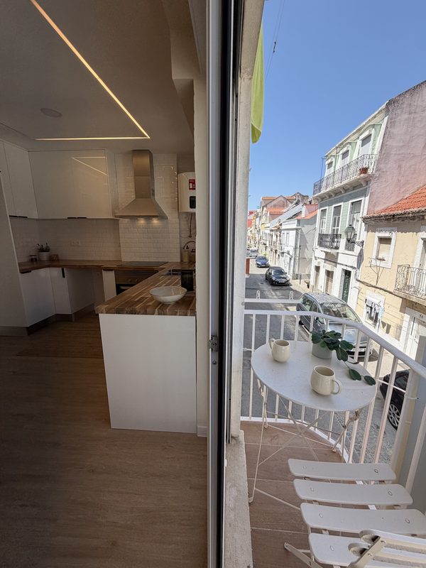 Porta da varanda aberta sobre a rua, com a cozinha à esquerda