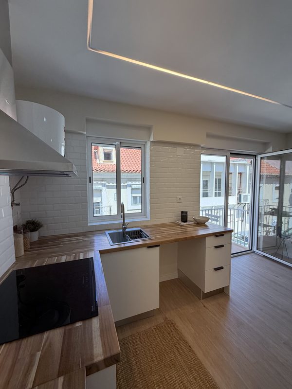 Cozinha com bancada de madeira, janela e saída para a varanda