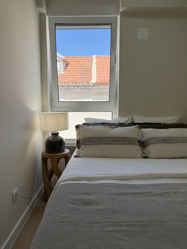 Cama de casal junto à janela, sobre os telhados do Seixal